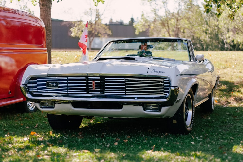 a classic car parked next to a red truck