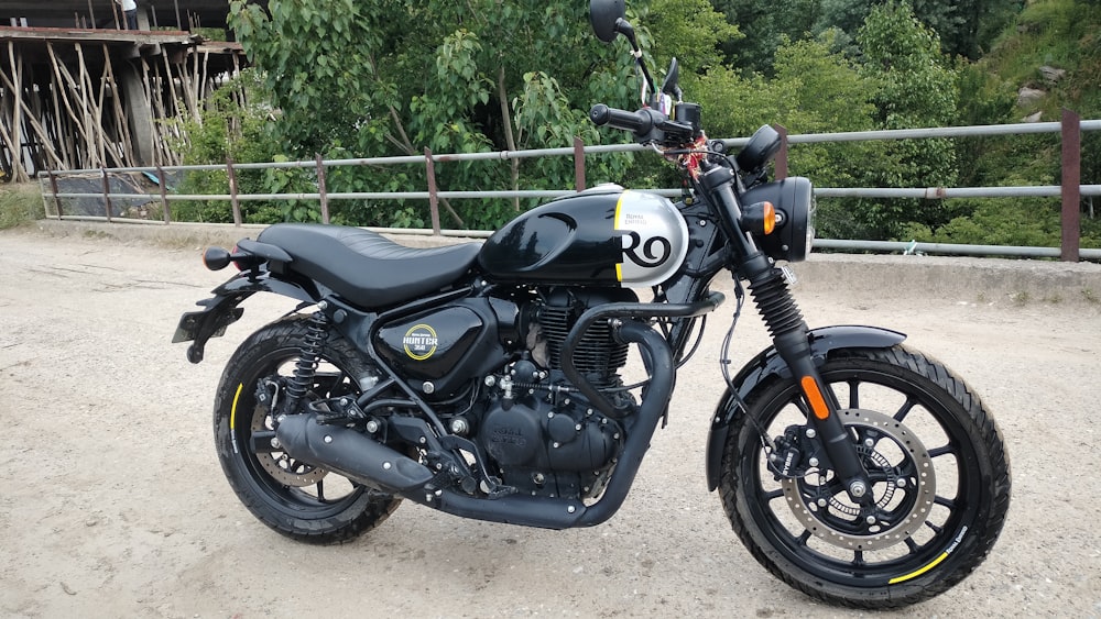 a motorcycle parked on a dirt road next to a fence