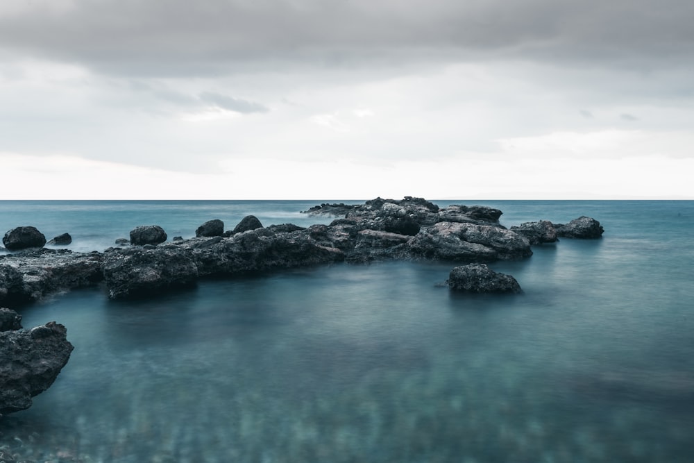 a body of water surrounded by rocks under a cloudy sky