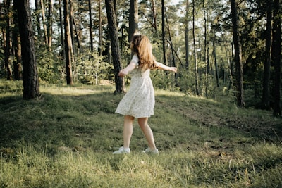 A young woman twirling in a flowing, vibrant summer dress with golden sunlight behind her