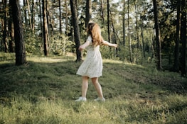 A happy young woman twirling in a soft pastel dress outdoors.