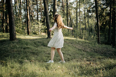 Young woman in a lavender flowy dress twirling outdoors with soft sunlight.