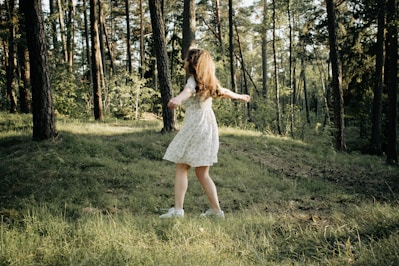A young woman twirling in a flowing, vibrant summer dress with golden sunlight behind her