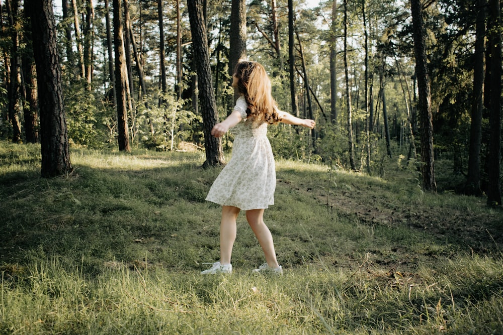 a woman in a dress standing in a forest