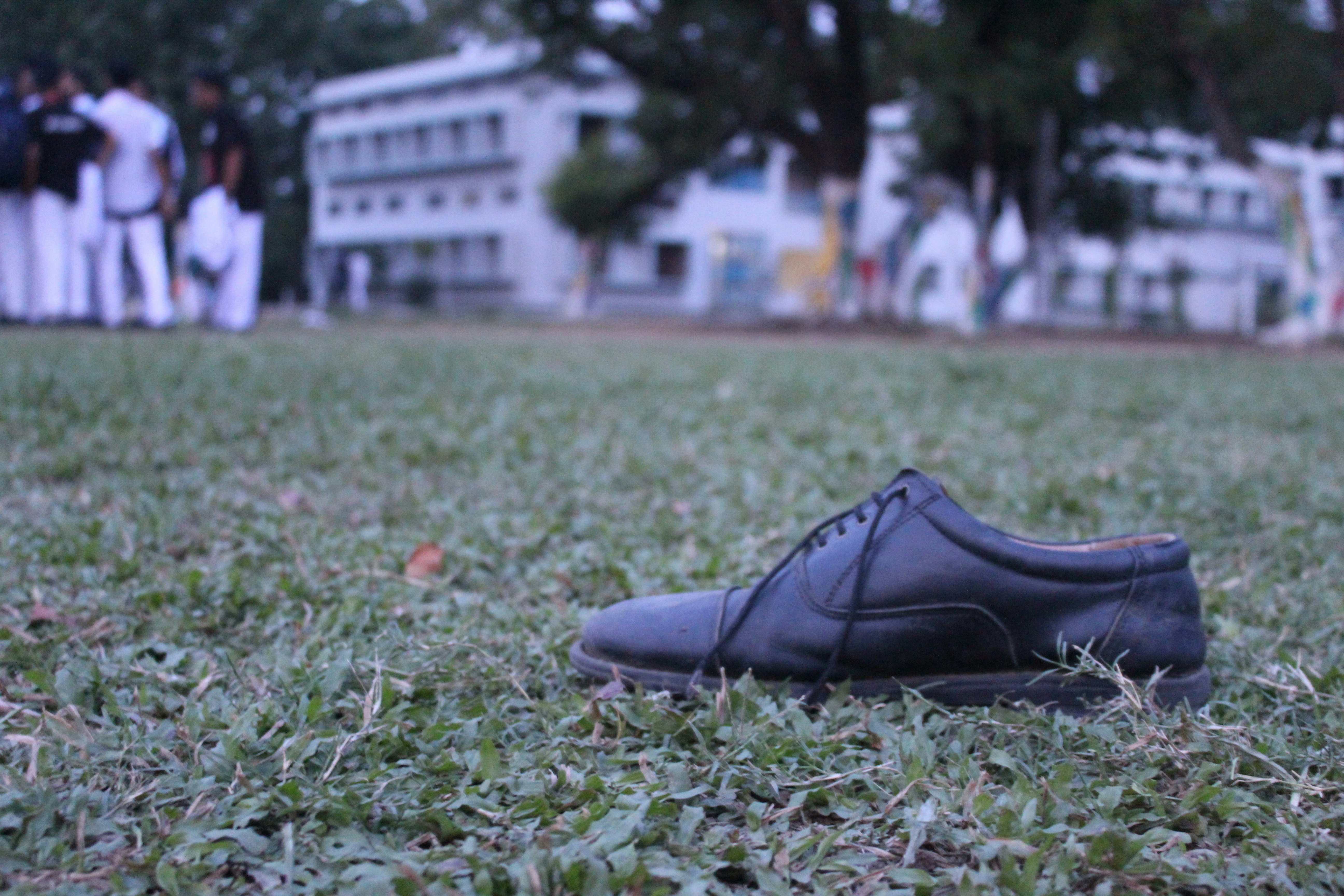 Pair of new black school shoes next to a folded school uniform on a bed in soft morning light