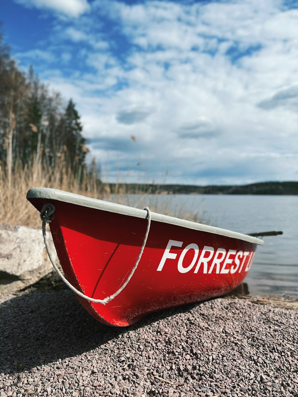 a red canoe sitting on the shore of a lake