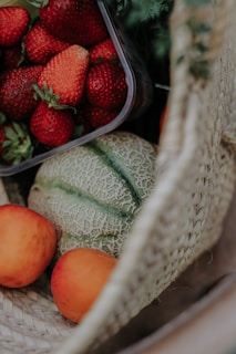 Freshly picked organic fruits spilling out of a woven basket on a sunlit kitchen counter.