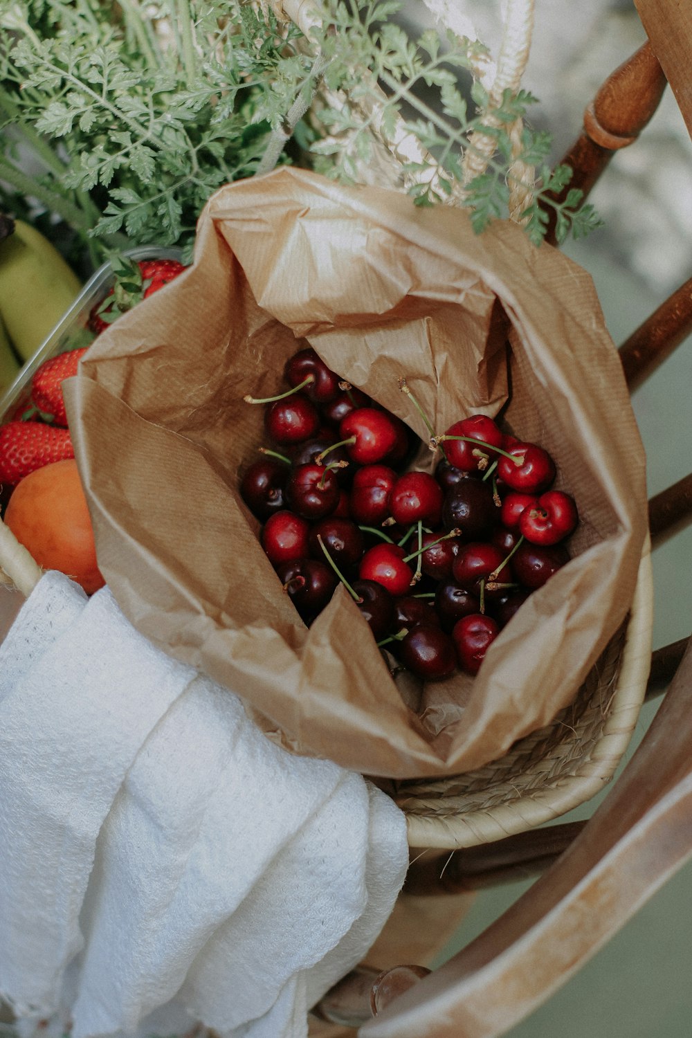 a bag of cherries sitting on top of a wooden chair