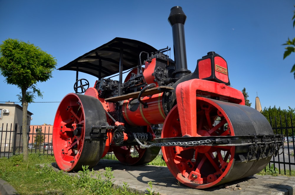 Un motore a vapore rosso e nero seduto in cima a un marciapiede