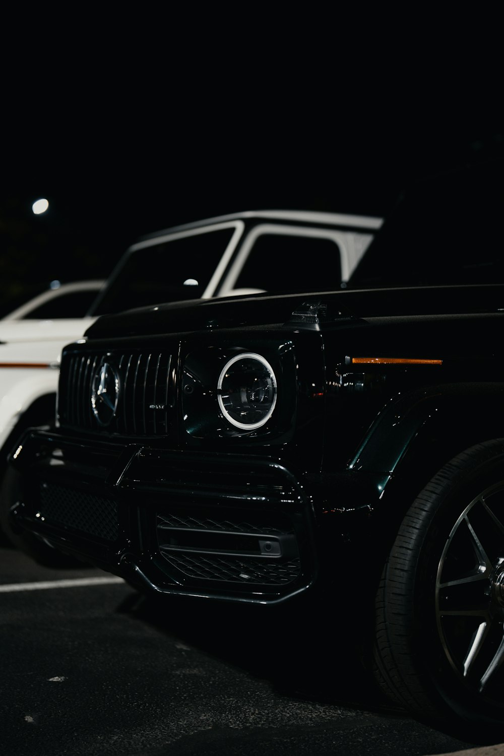 a black jeep parked in a parking lot at night
