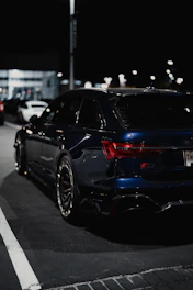 A valet carefully parking a car at night with city lights in the background.