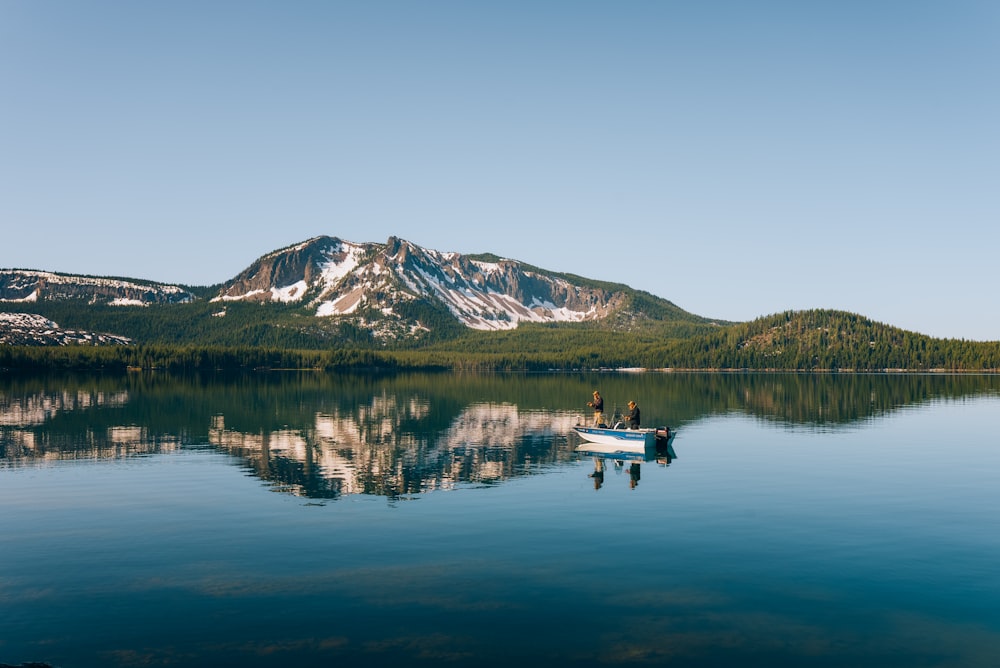 two people in a boat on a lake with mountains in the background