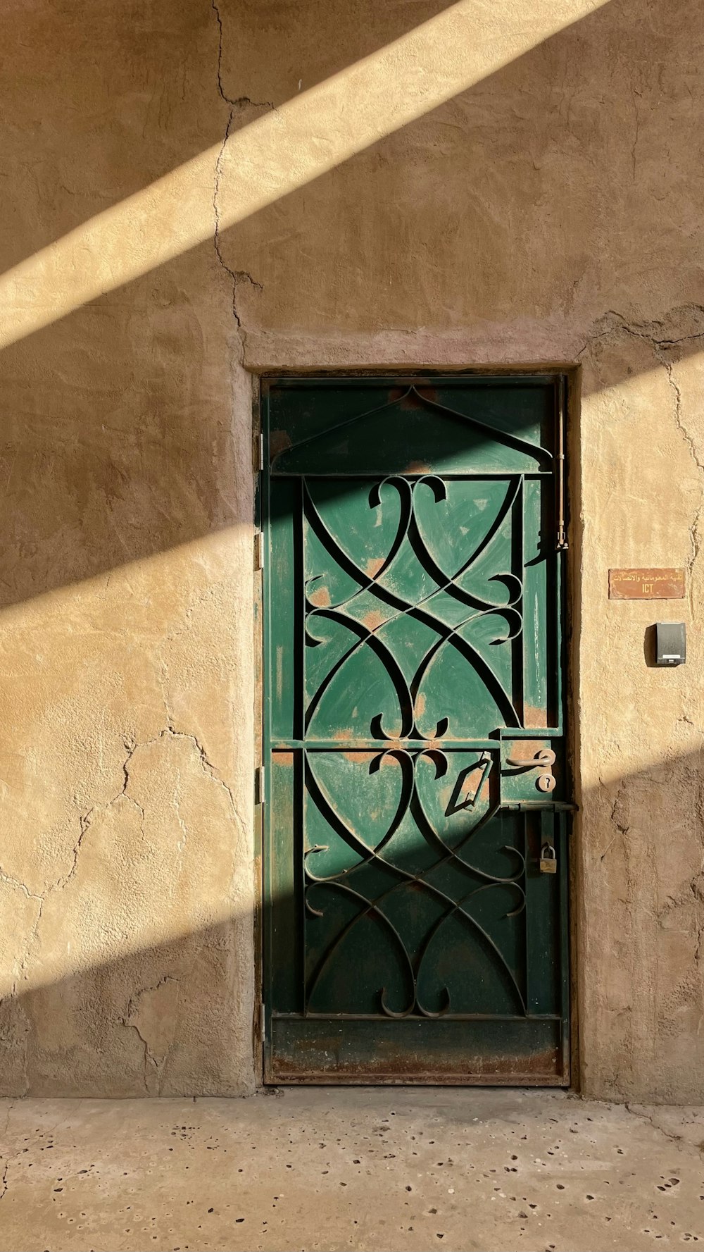 a green door with a wrought iron design