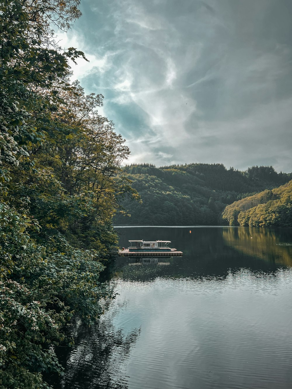 a boat floating on top of a lake surrounded by trees