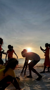 Kids enjoying team-building activities on the beach at sunset.