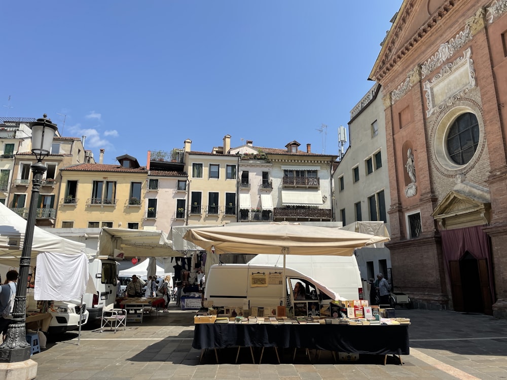 an outdoor market with tables and umbrellas in front of a building