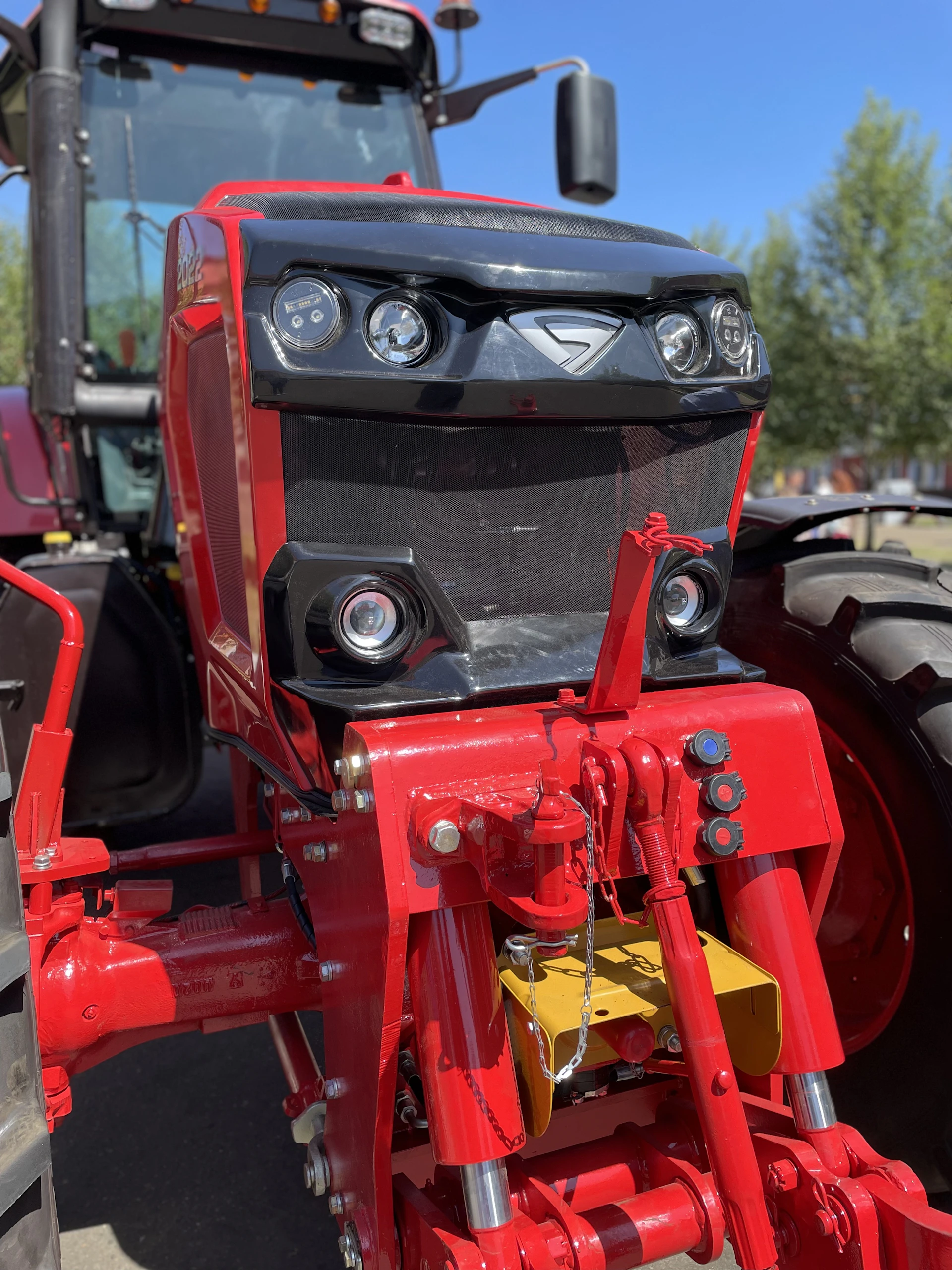 Close-up of a large tractor undergoing mechanical maintenance with tools and technicians working carefully.