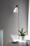 A sleek modern LED floor lamp standing tall beside a comfy armchair in a minimalist room.