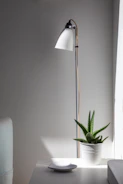A sleek modern LED floor lamp standing tall beside a comfy armchair in a minimalist room.