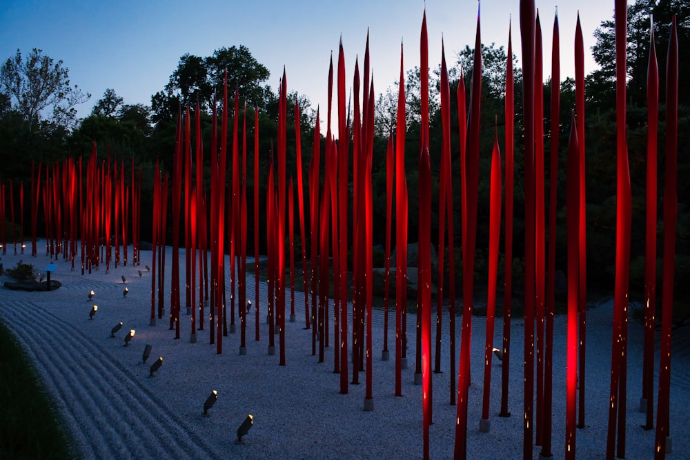 a large group of red poles in the middle of a park