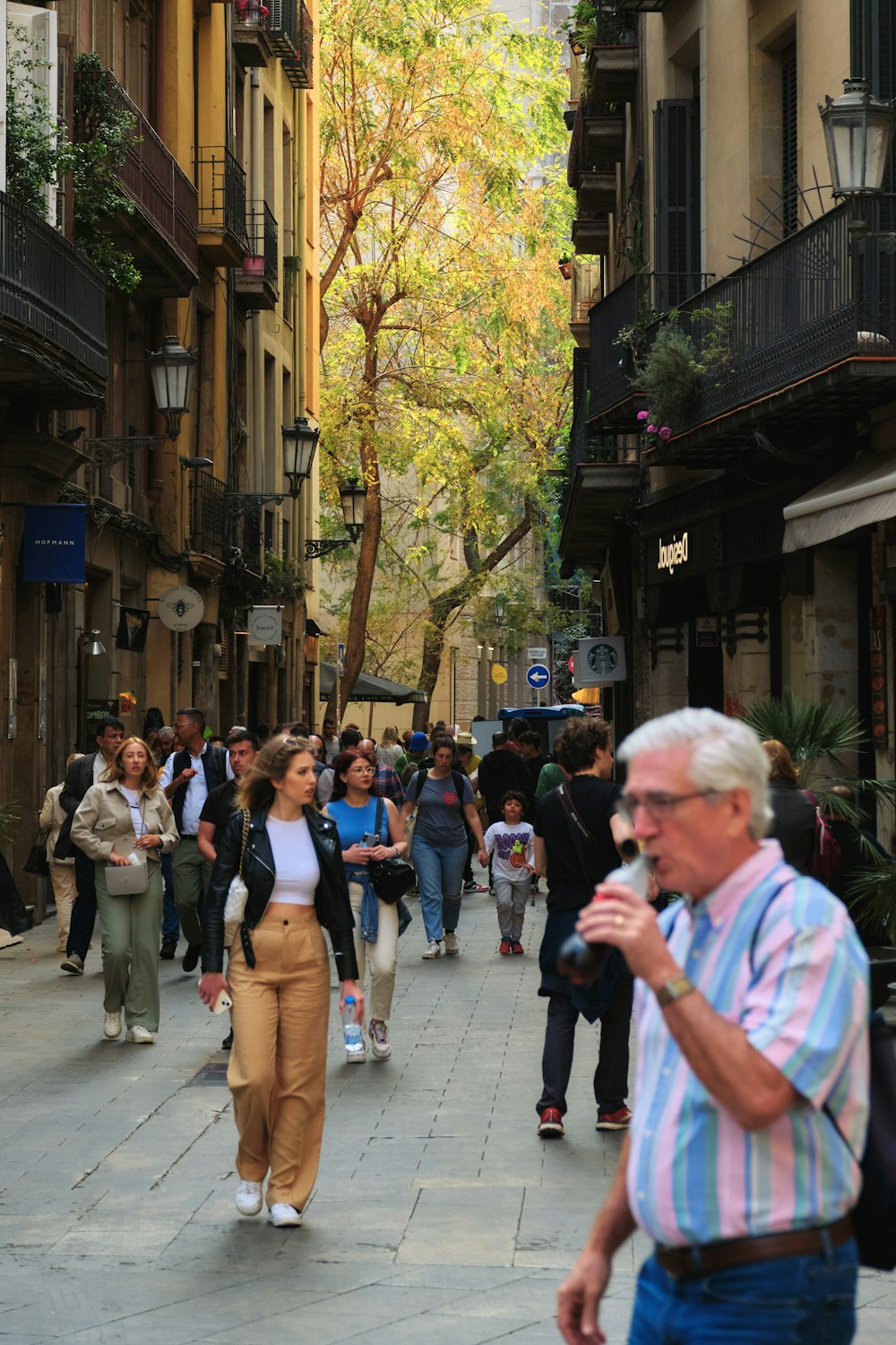 a group of people walking down a street next to tall buildings