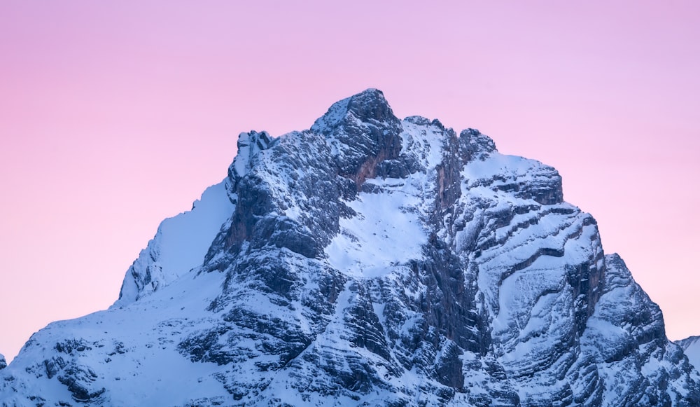 a snow covered mountain with a pink sky in the background