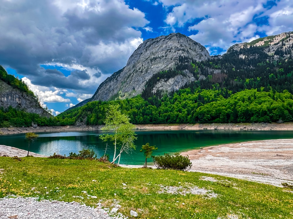 a lake surrounded by mountains under a cloudy sky