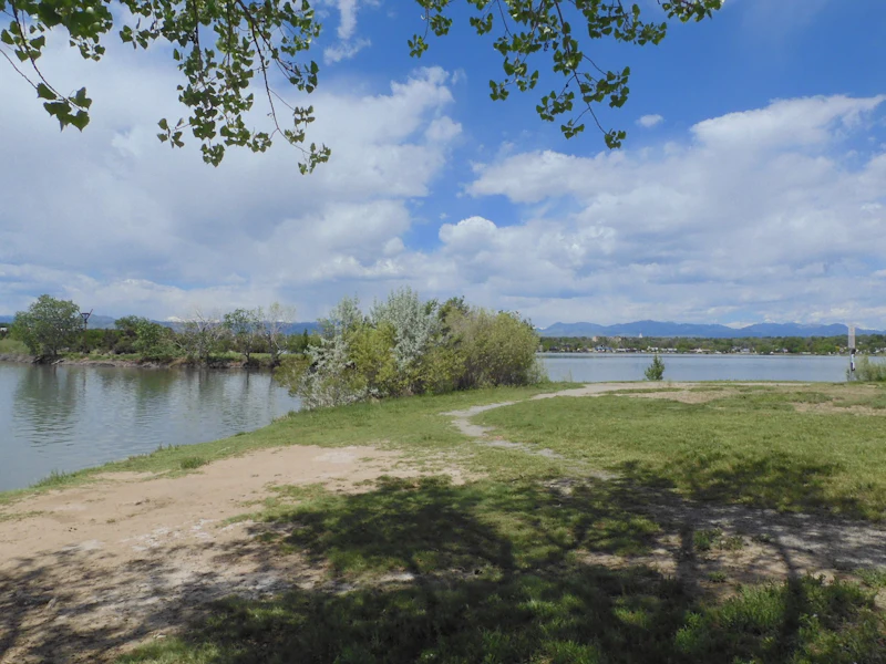 Open green parkland beside a calm lake