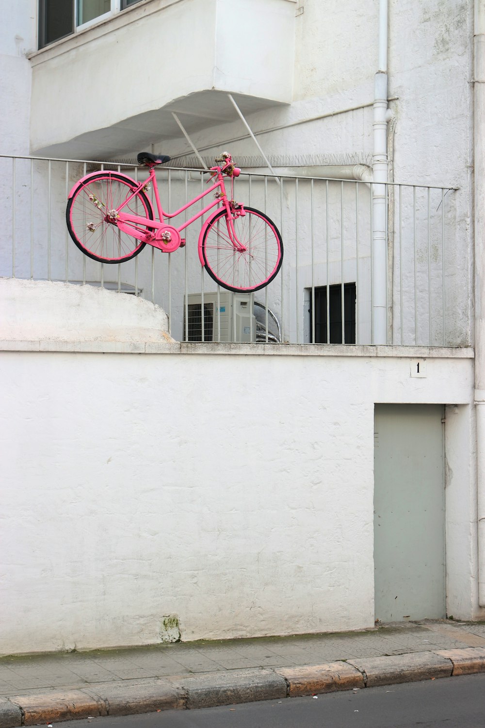 a pink bike hanging from the side of a building