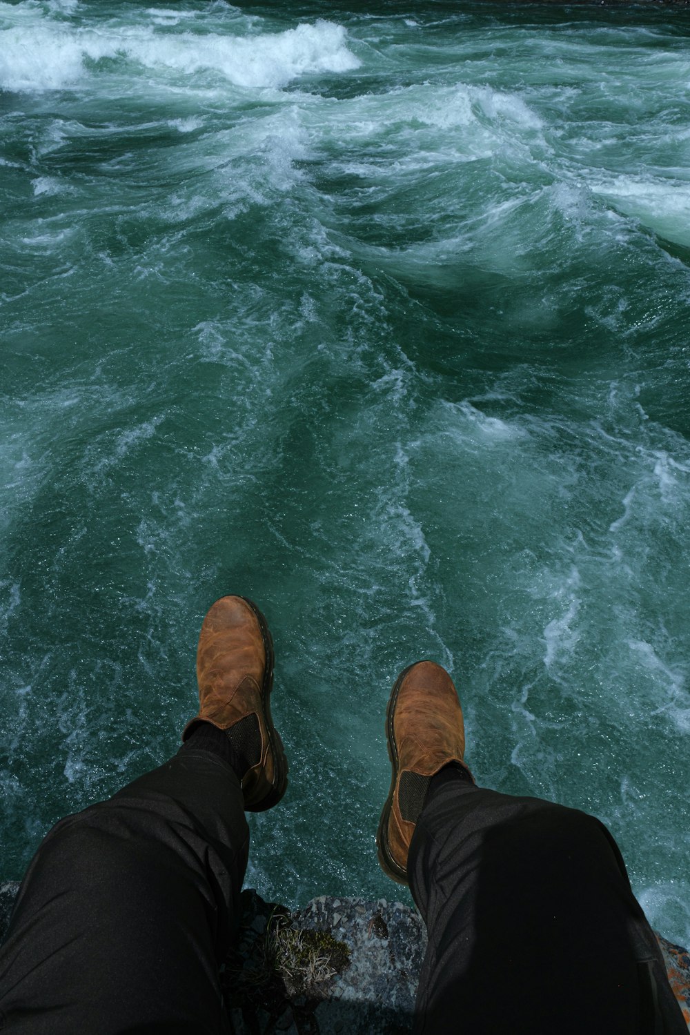 a person standing on a rock next to a body of water