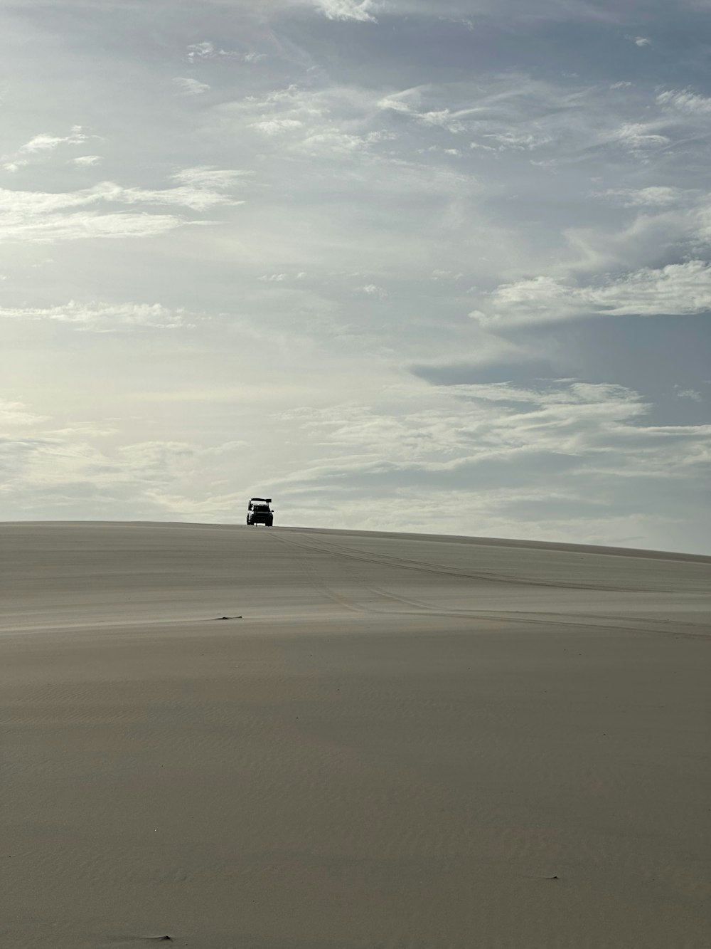 um caminhão atravessando um campo de areia sob um céu nublado