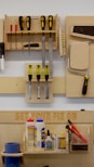 A neatly organized wall-mounted tool rack featuring various hand tools such as screwdrivers, files, brushes, and a saw. Below, there is a shelf with numerous glue bottles, adhesives, and a pair of red-handled pliers. The phrase 'GET YOUR FIX ON' is engraved on a wooden board above the shelf.