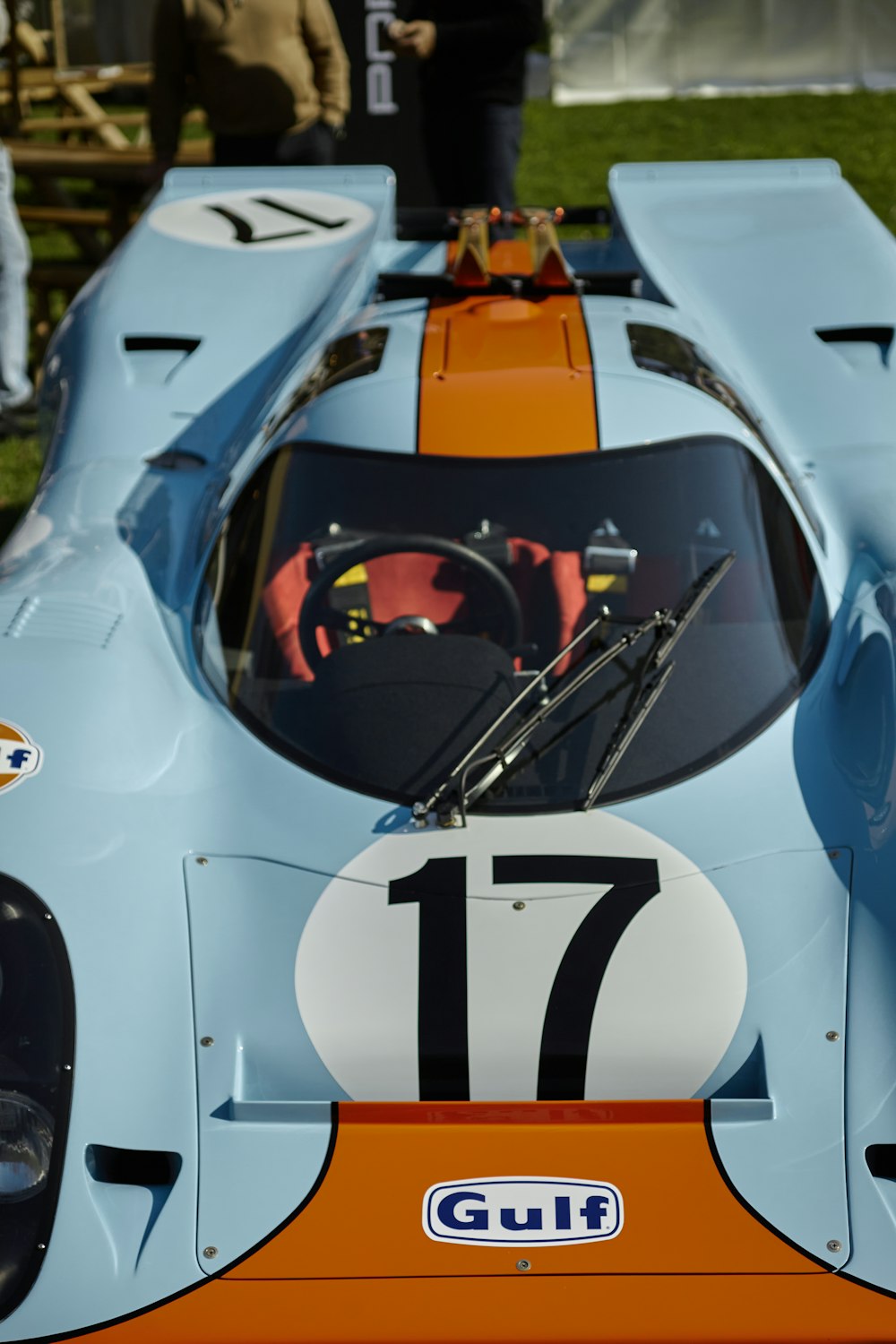 a blue and orange race car sitting on top of a grass covered field