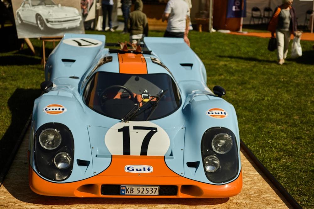 a blue and orange race car sitting on top of a grass covered field