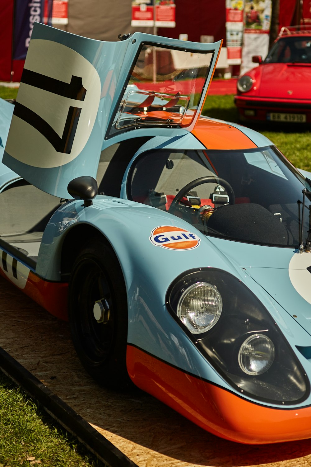 a blue and orange race car sitting on top of a lush green field