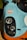 The image showcases a close-up view of the front portion of a vintage racing car adorned with a Gulf logo. The car features a distinctive color scheme of light blue and orange, highlighting its retro aesthetic. Prominent circular headlights are positioned against a black background, contributing to the car's classic racing look.