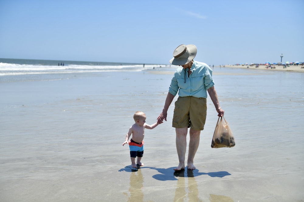 a woman and a child are walking on the beach