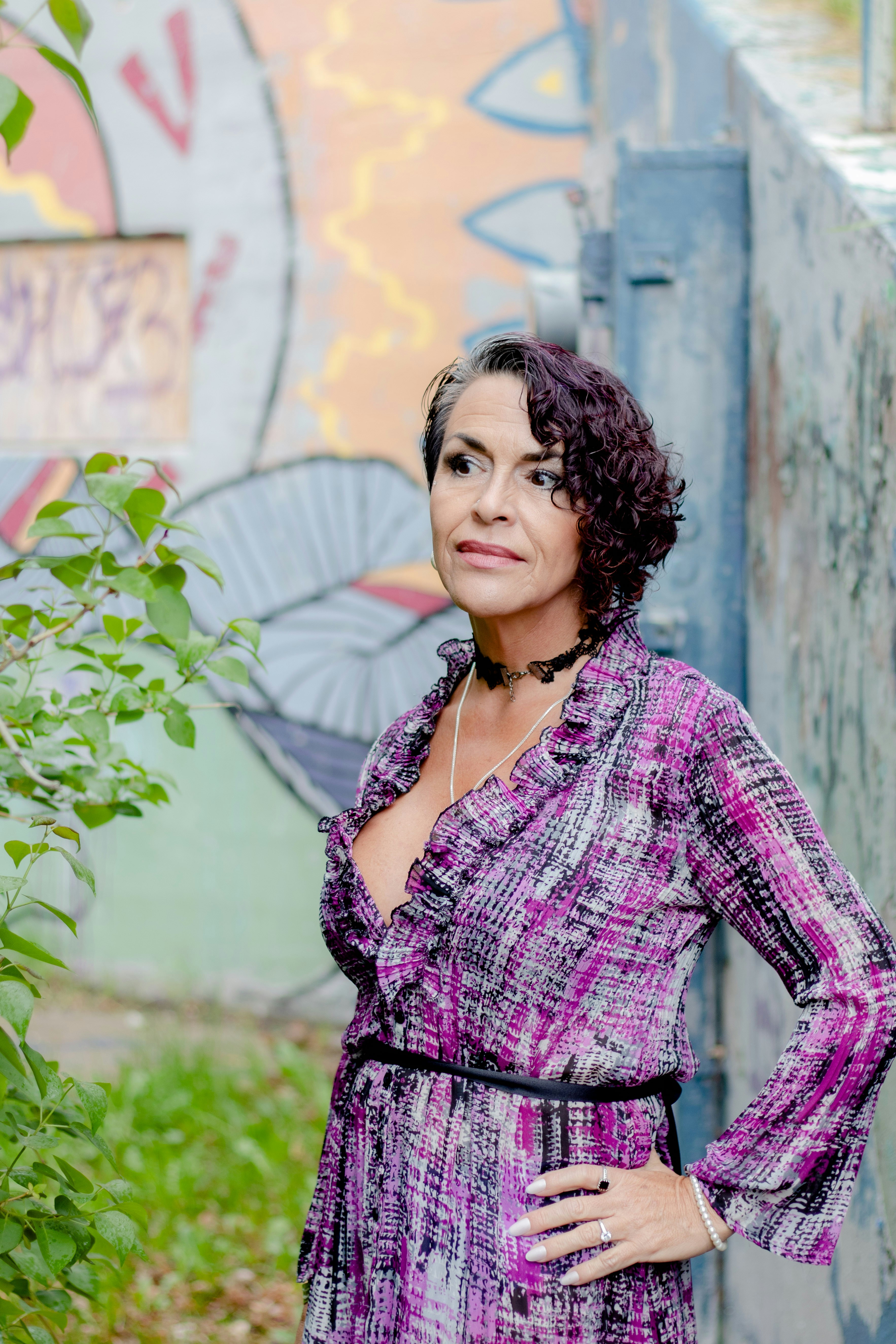 A woman in a purple dress standing in front of a wall photo – Free ...