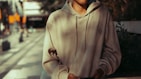 a man in a hoodie standing on a city street