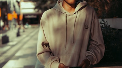 Model wearing a beige off-white hoodie in an urban street setting