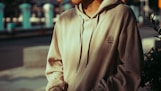 a man in a hoodie is standing on the street