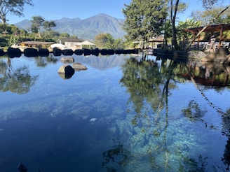 A peaceful trout pond reflecting the clear blue sky with mountains in the background.