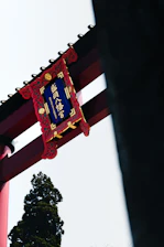 Stylized illustration of a Japanese torii gate with cherry blossoms and waves in a modern flat design.