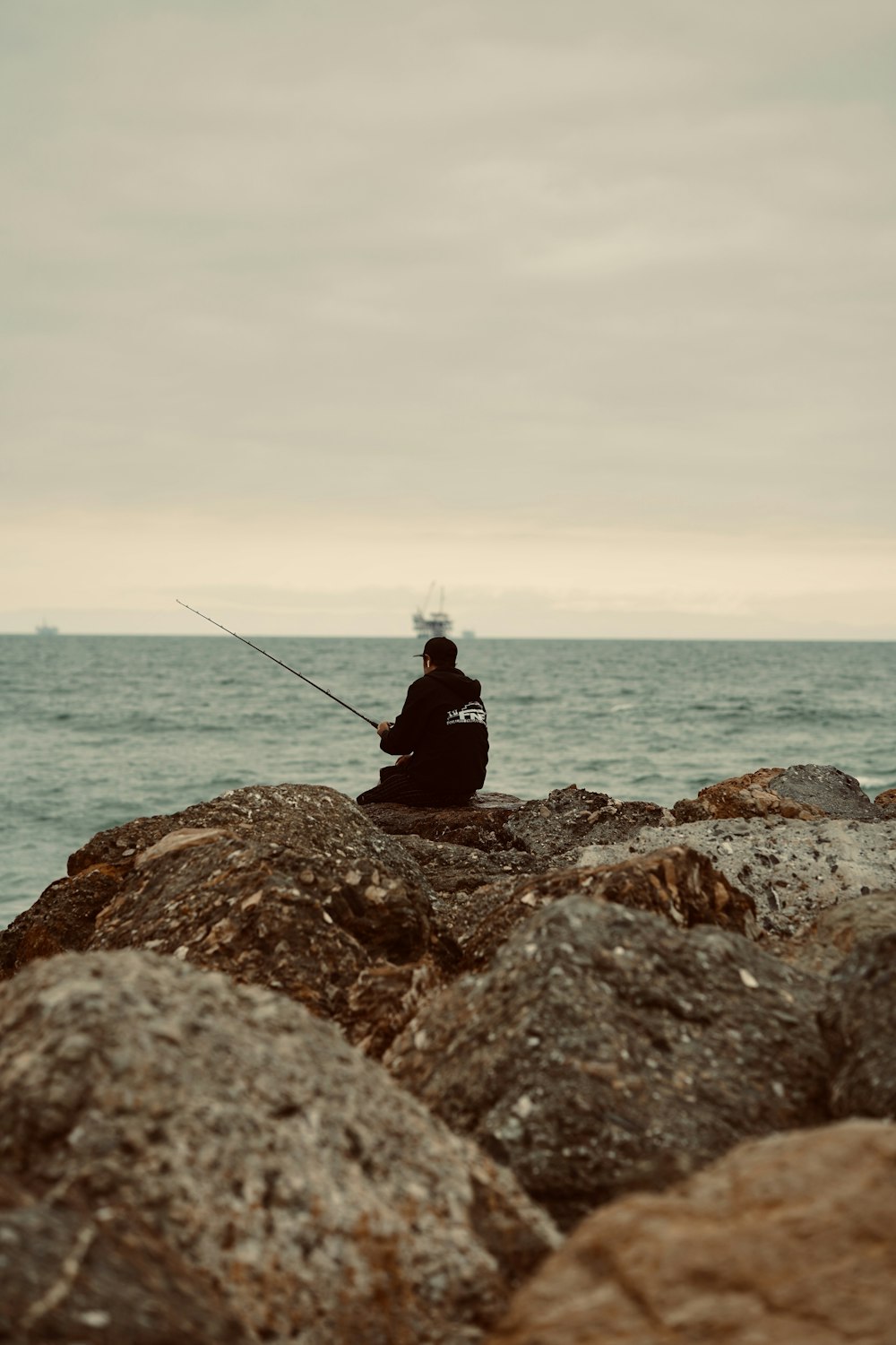 a man sitting on top of a rock next to the ocean