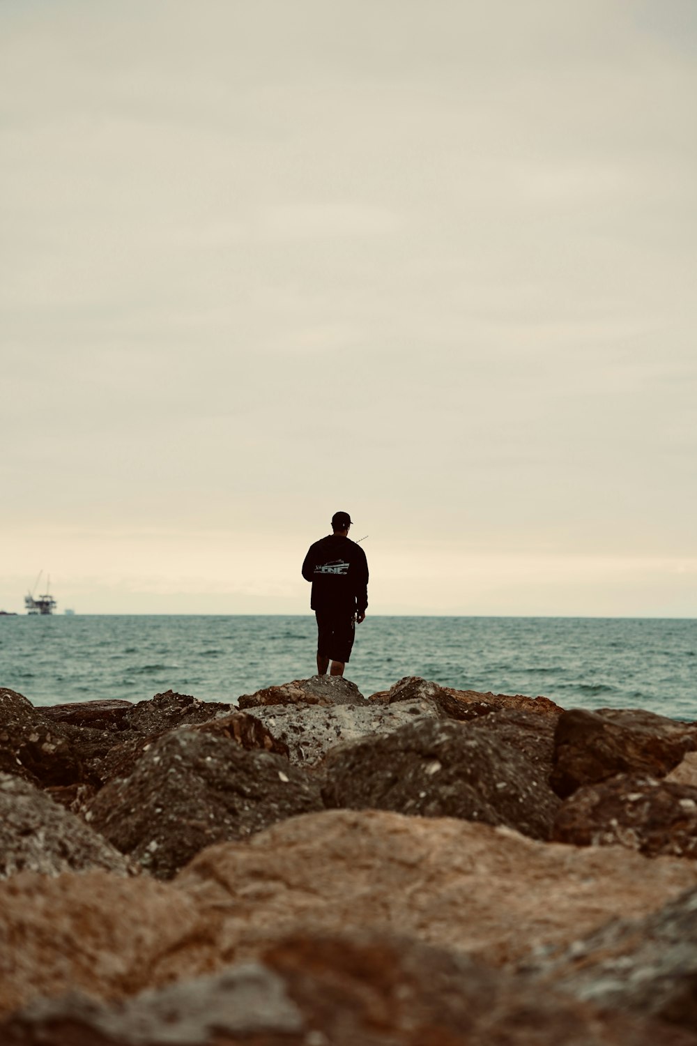 a man standing on top of a rocky beach next to the ocean