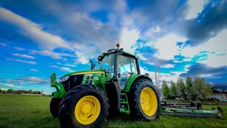 Modern farm machinery parked beside a field under a bright sky.