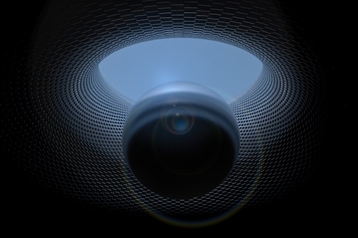 A surreal digital artwork featuring a spherical object positioned centrally, surrounded by a patterned, tunnel-like structure. The texture of the tunnel resembles a grid or mesh, creating a sense of depth and movement. Lighting effects enhance the mysterious and futuristic atmosphere.
