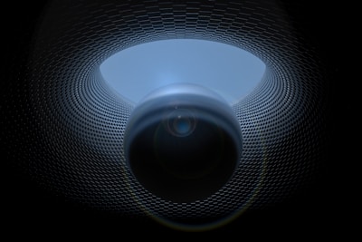 A surreal digital artwork featuring a spherical object positioned centrally, surrounded by a patterned, tunnel-like structure. The texture of the tunnel resembles a grid or mesh, creating a sense of depth and movement. Lighting effects enhance the mysterious and futuristic atmosphere.