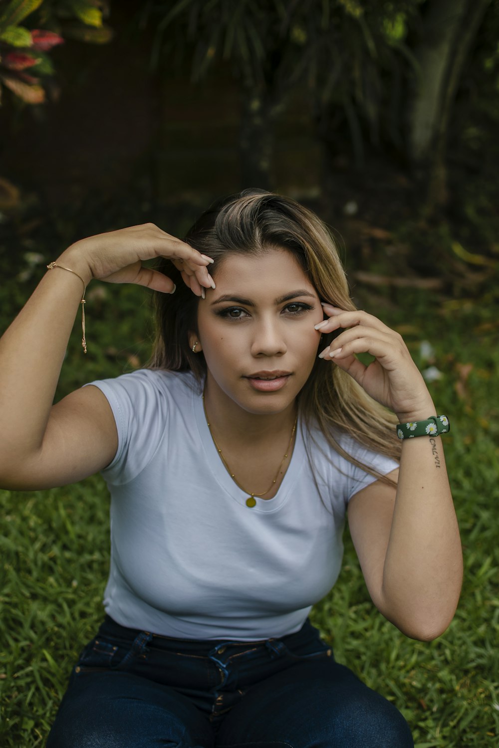 a woman sitting in the grass with her hand on her head