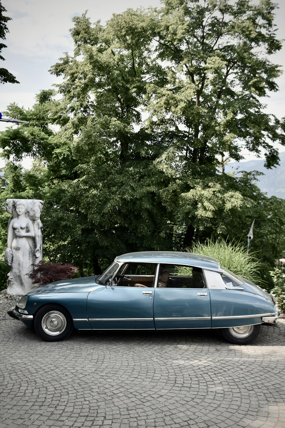 a blue car parked in front of a statue